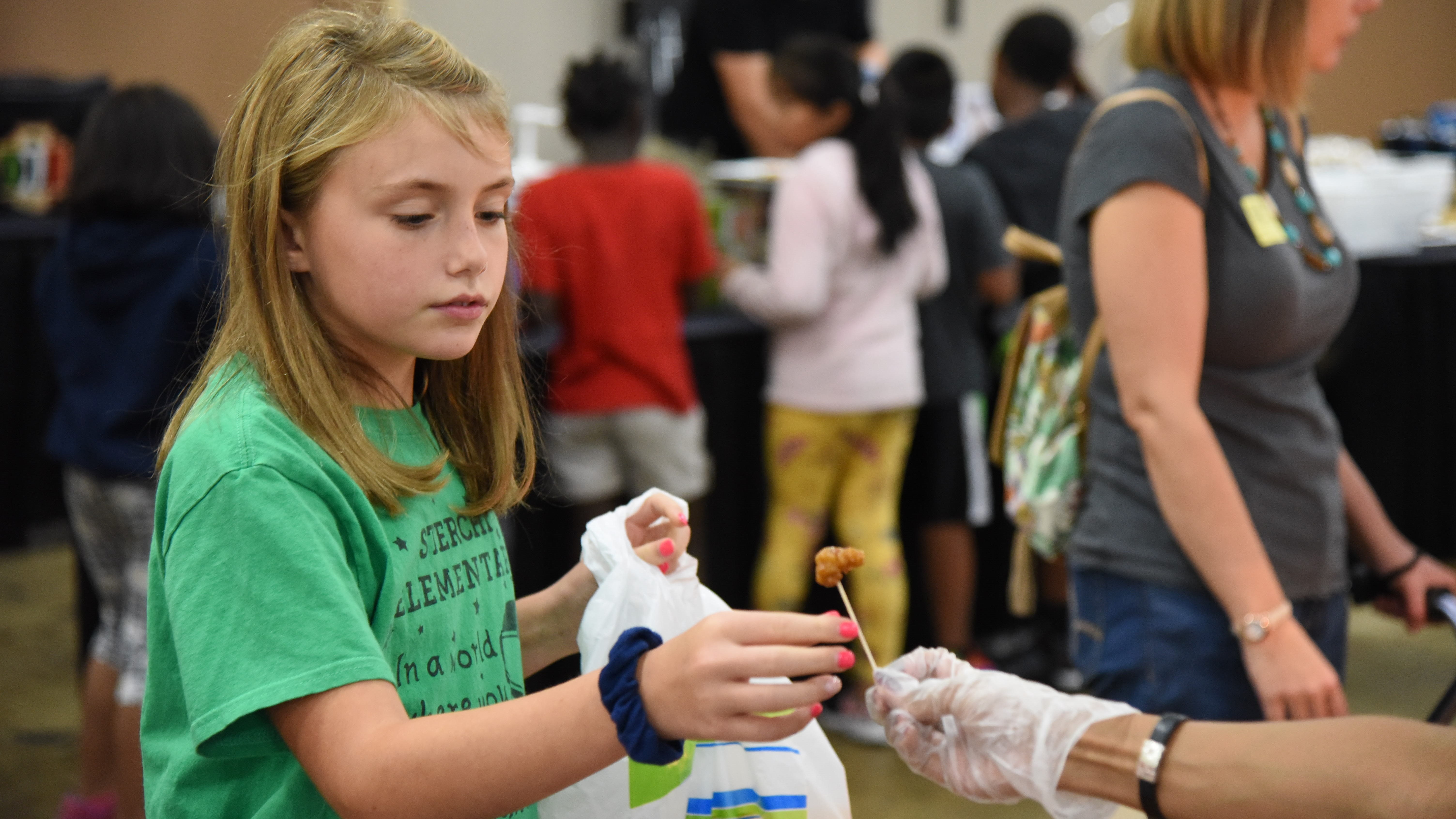 Pyper Clevinger, a 4th-grader at Sterchi Elementary, samples a bite of Tangerine Chicken at the KCS Food Show on Sept. 12, 2019. 